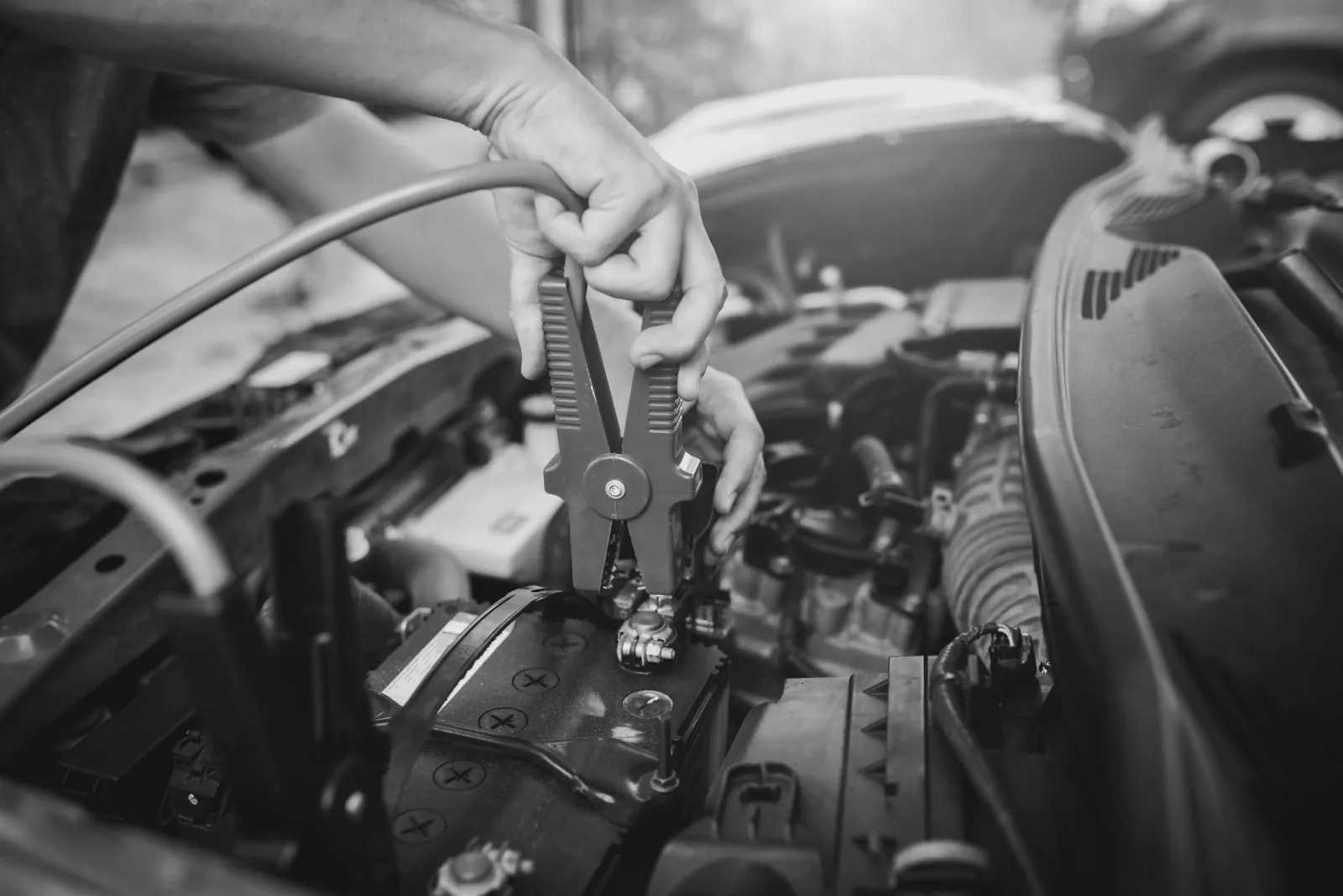 De klem van een startkabel wordt op de pluspool van een lege auto-accu gezet